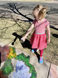 Child interacts with a colorful chalk mural