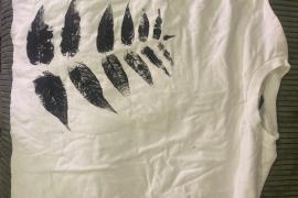 Foto de una camiseta blanca con una impresión de hojas negras que cubre el lado izquierdo de la camisa.