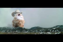Sombrero de vaquero con gato gritando detrás de una cadena montañosa frente a un cielo gris y lúgubre