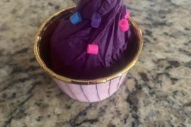 A cupcake with sprinkles and a cherry on top.