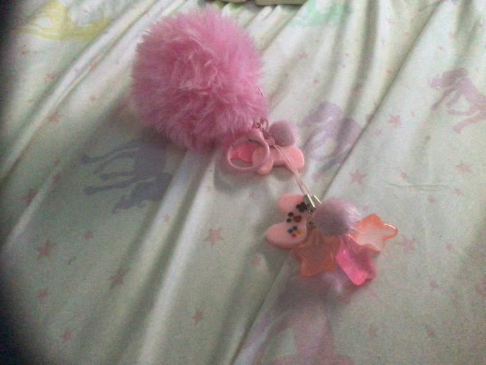 Móc khóa được làm tại nhà, màu hồng với một quả pom pom mịn ở trên cùng với bùa điều khiển trò chơi điện tử màu hồng, ngôi sao và pom pom mini màu hồng nhạt