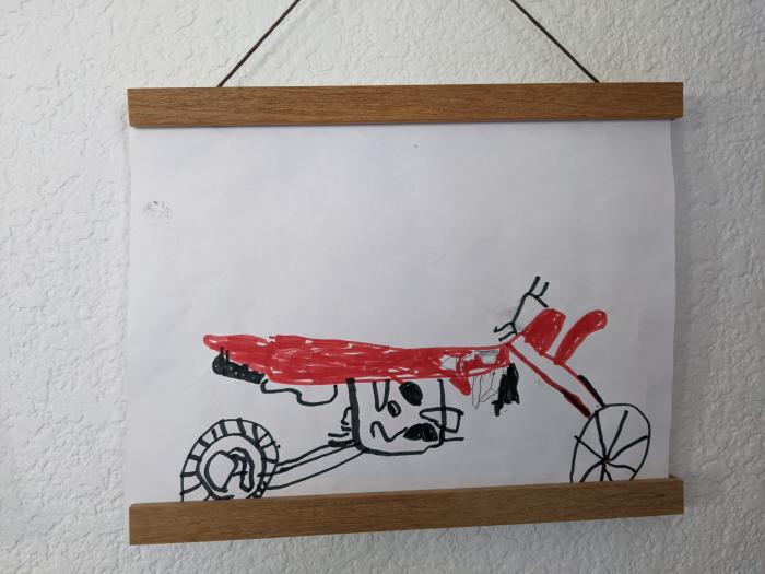 A detailed black marker drawing of a dirt bike with a red marker seat.