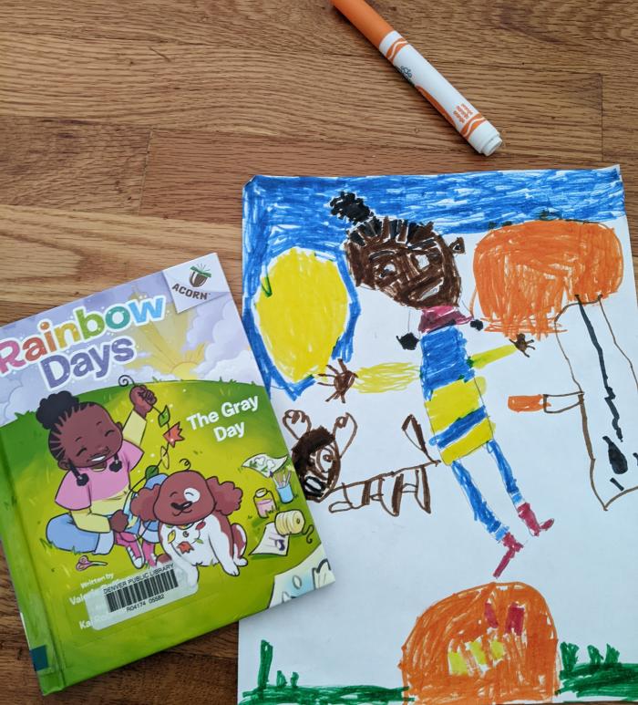 A marker drawing of Zoya, a Black girl with a high puff hairstyle, standing next to a brown dog. The book cover of Rainbow Days: The Gray Day is next to the drawing.