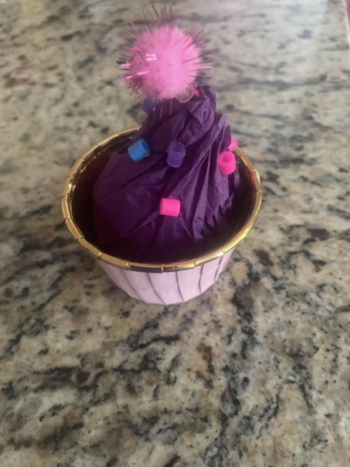 Một chiếc bánh cupcake với rắc và một quả anh đào lên trên.